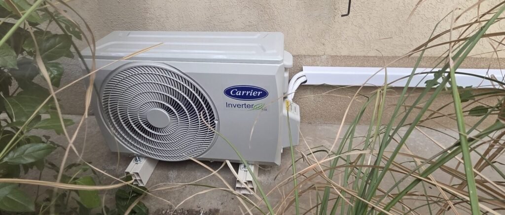 Unité extérieure Carrier Inverter posée sur supports au pied d’une façade, installation réalisée à Caluire-et-Cuire