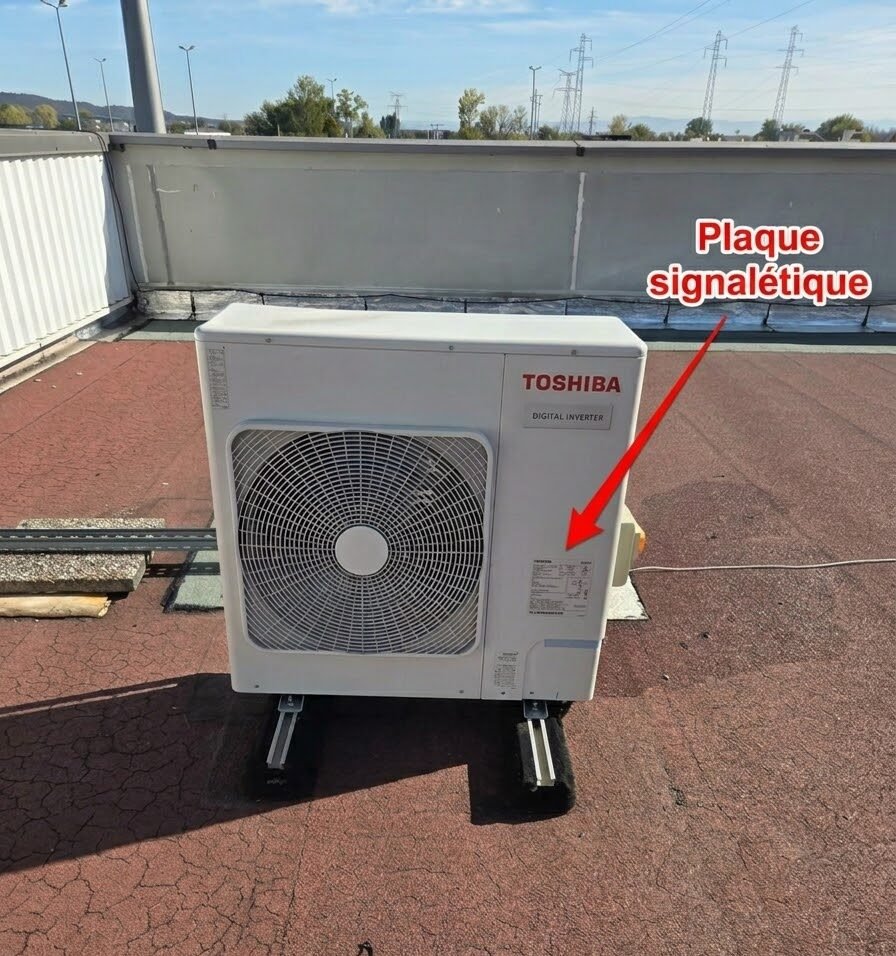 Unité extérieure Toshiba sur un toit-terrasse, avec une flèche indiquant l’emplacement de la plaque signalétique